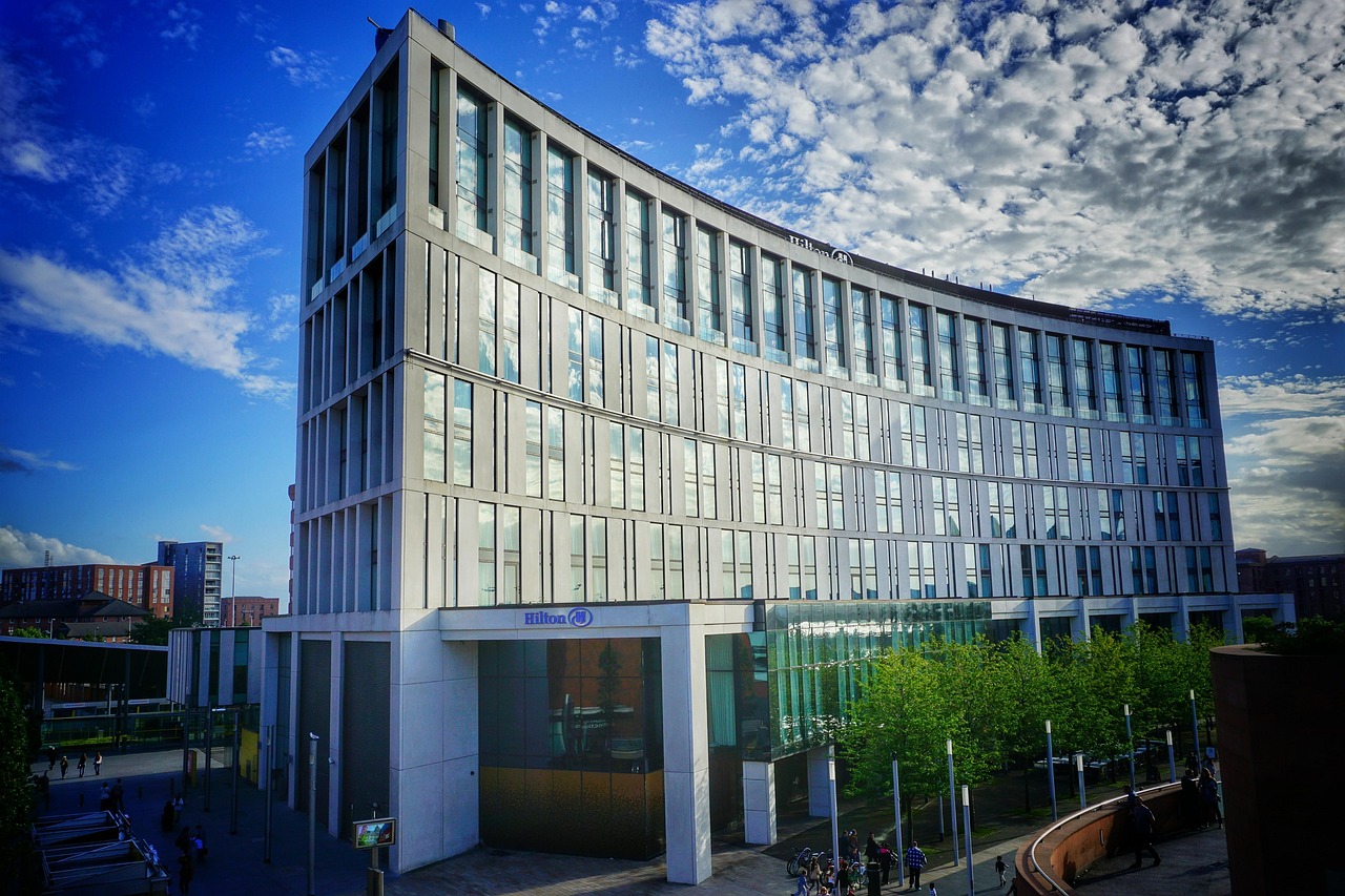 Modern Hilton hotel building with curved glass façade under blue sky.